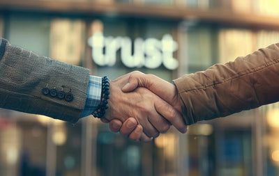 Photograph of hands shaking in front of Trust sign